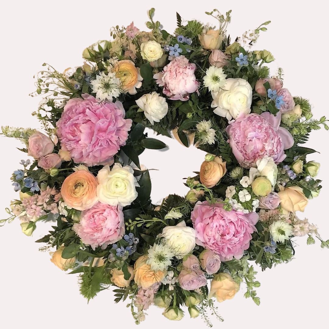 Blomsterkransen er sammensat af blomster i blide pastelfarver, der giver den et roligt og harmonisk udtryk. Pastelfarver er kendt for deres blide og beroligende egenskaber. blomster til begravelse.