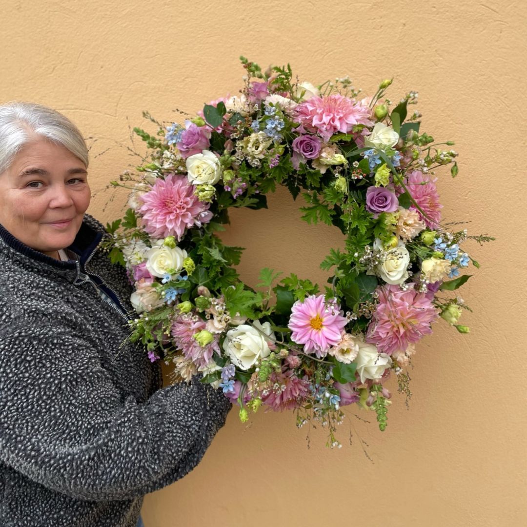 Blomsterkransen er sammensat af blomster i blide pastelfarver, der giver den et roligt og harmonisk udtryk. Pastelfarver er kendt for deres blide og beroligende egenskaber. blomster til begravelse.