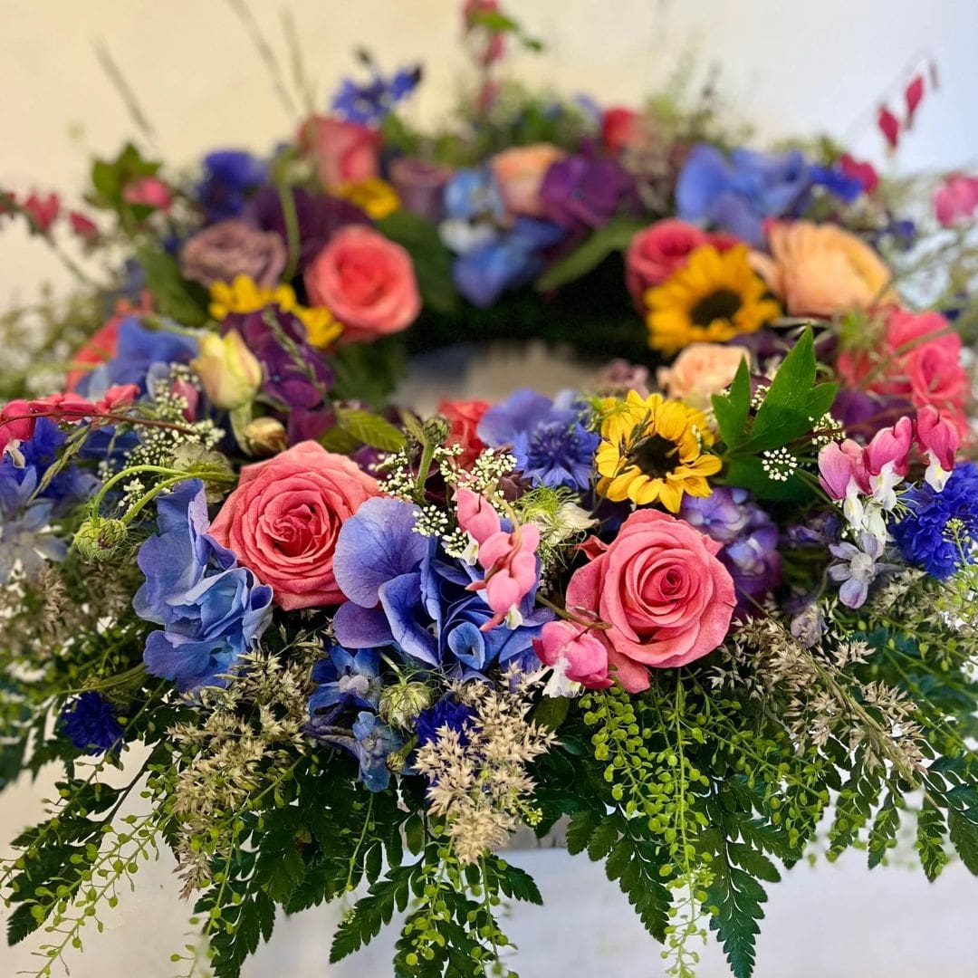 Blomsterkrans til begravelse i mange farver, i kenzo og multifarvede blomster